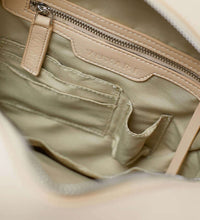 Load image into Gallery viewer, The inside of a cream vegan leather shoulder bag showing a cream recycled plastic lining and silver zip and hardware.
