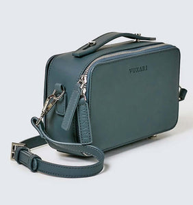 Teal blue vegan leather crossbody handbag against a white background.