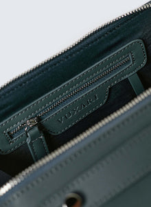 Teal vegan leather crossbody handbag showing recycled blue plastic lining with silver hardware photographed against a white background.